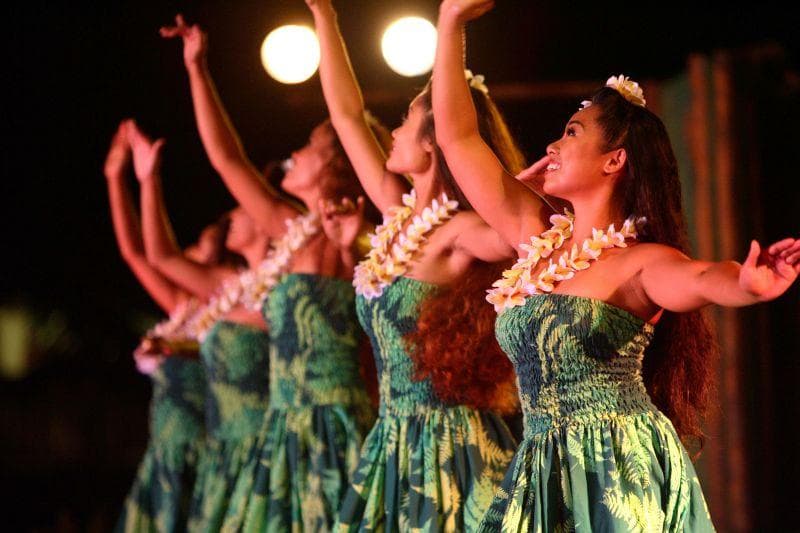 Female hula dancers performing in green gowns at evening luau