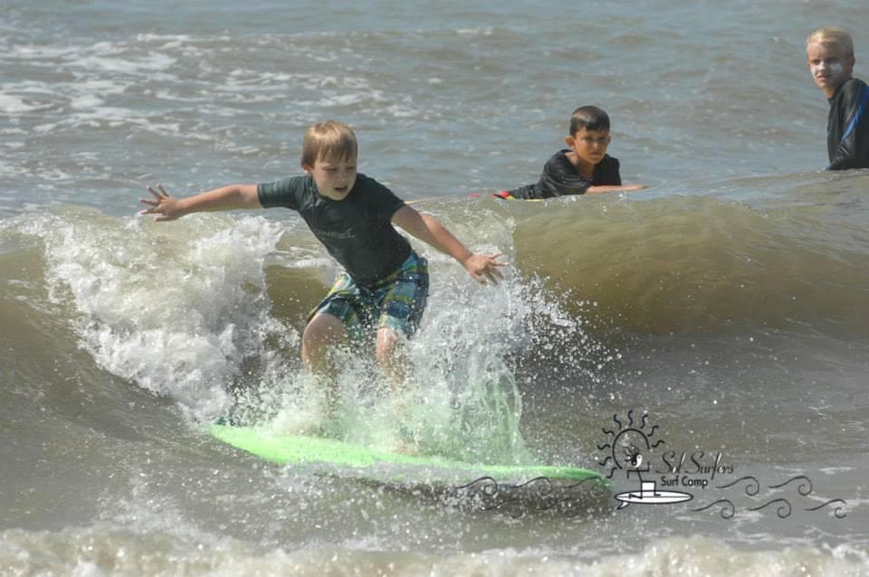 Boy surfing on a green board amid breaking shore waves