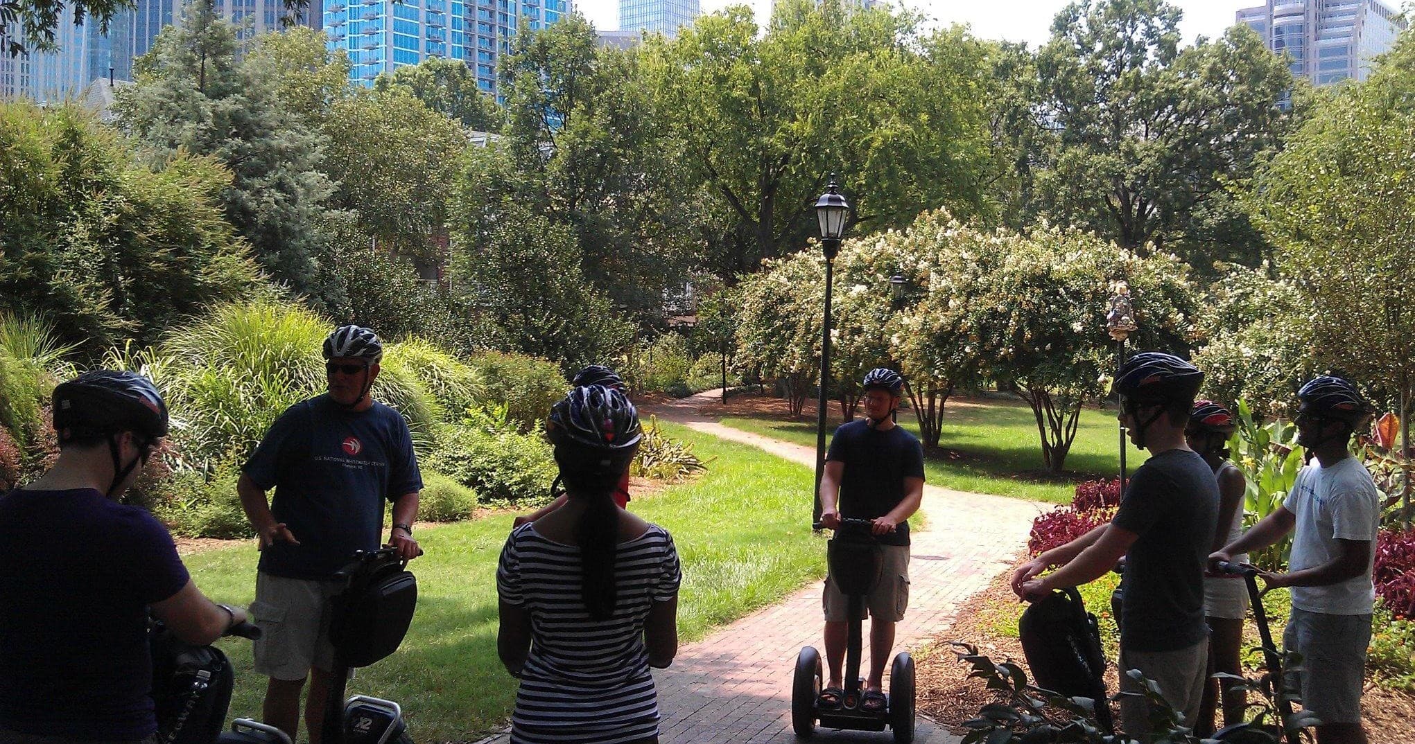 Guided scooter tour group riding through shaded city park