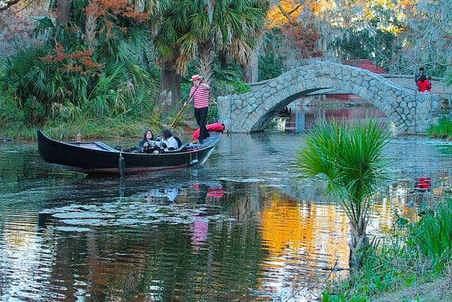 Gondola ride under stone bridge through scenic park lagoon