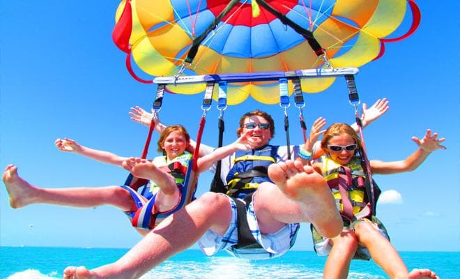 Parasailing over bright blue ocean with smiling riders in Key West