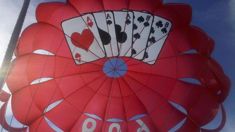 Close-up red parasail canopy with card design, sunny beach sky