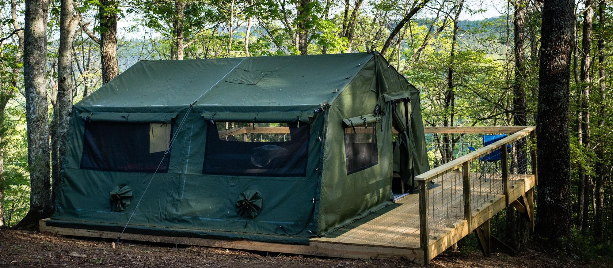 Canvas tent campsite on a wooden platform in dense forest shade