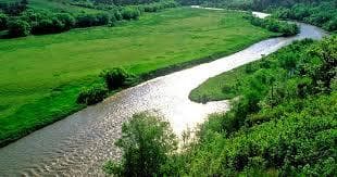 Scenic river bend with canoeing and green prairie shoreline