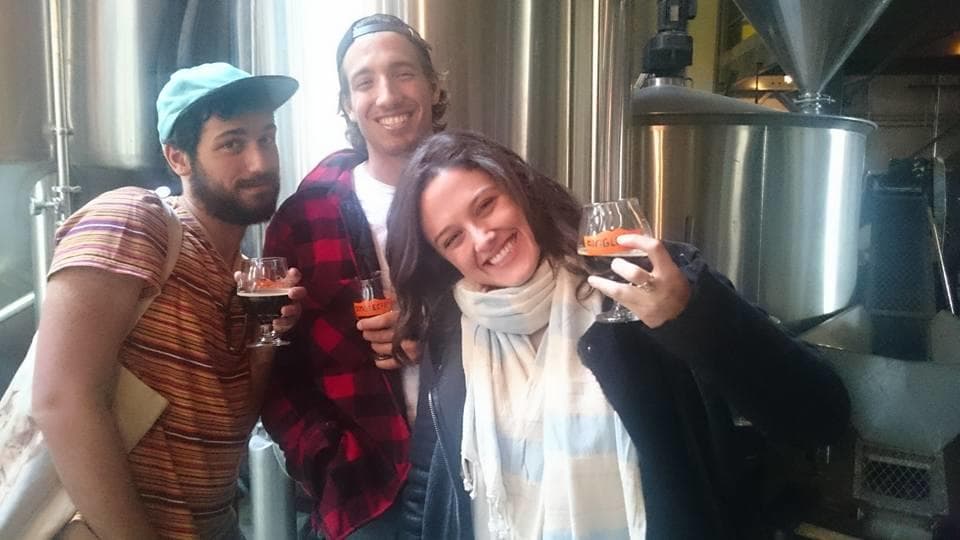 Friends sampling craft beer inside brewery by stainless tanks