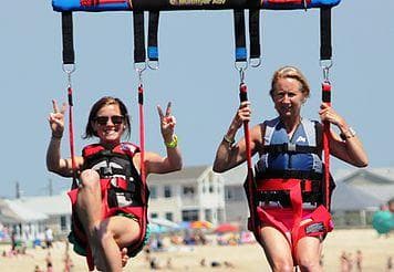 Pair parasailing over sandy Point Pleasant Beach shoreline