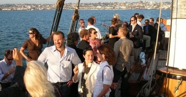 Group enjoying sunset sail aboard crowded deck on yacht
