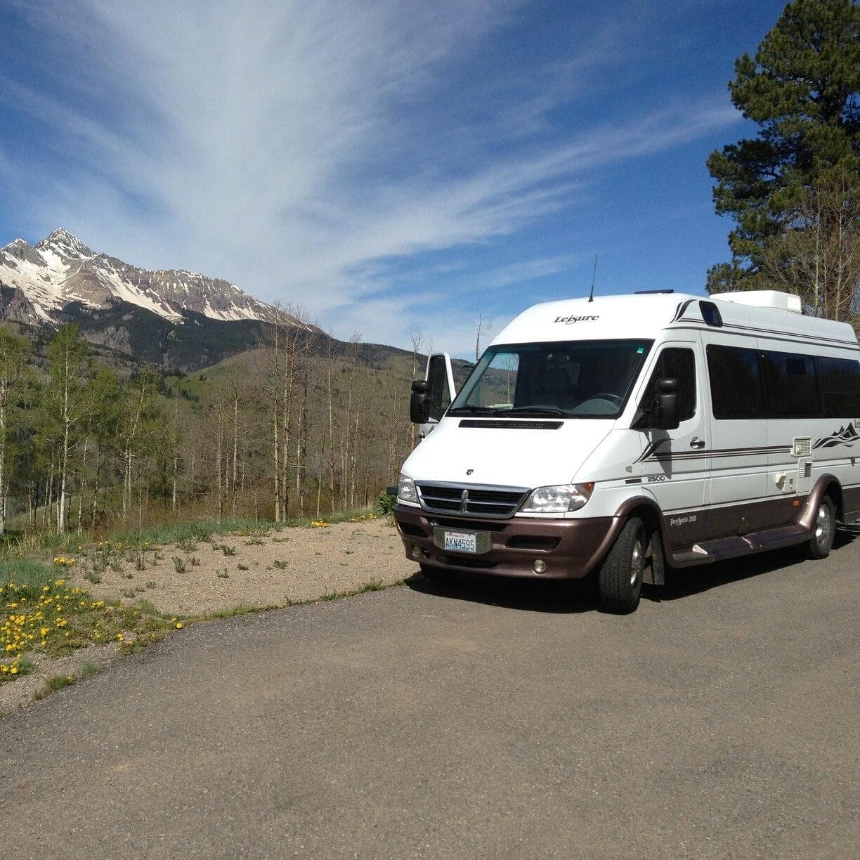 Mountain van parked near alpine trailhead with peak views