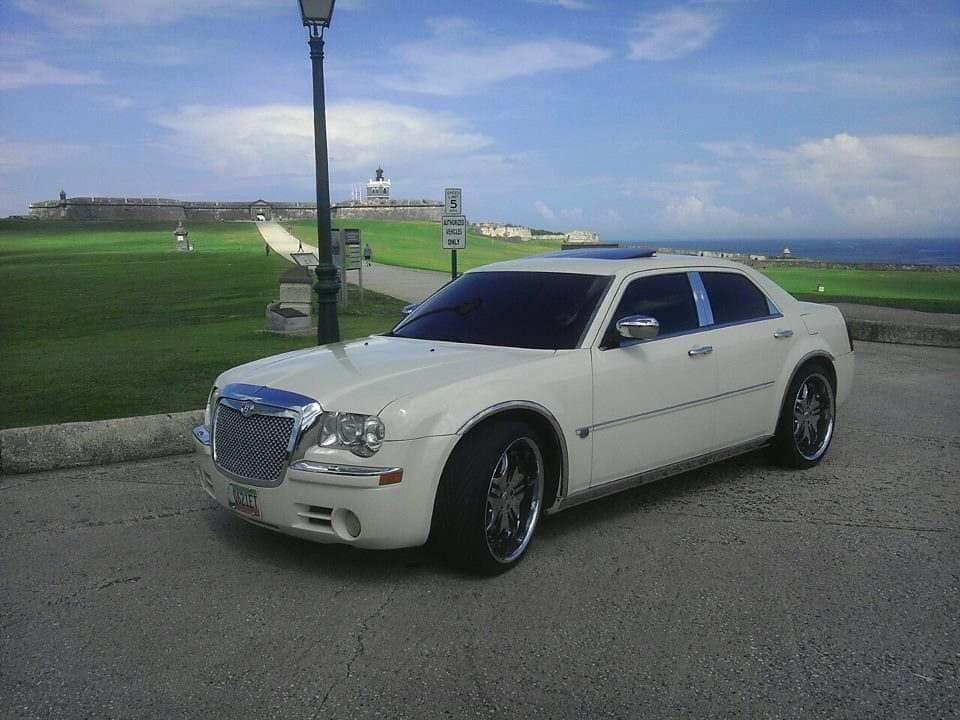 White sedan parked by seaside promenade with lighthouse view