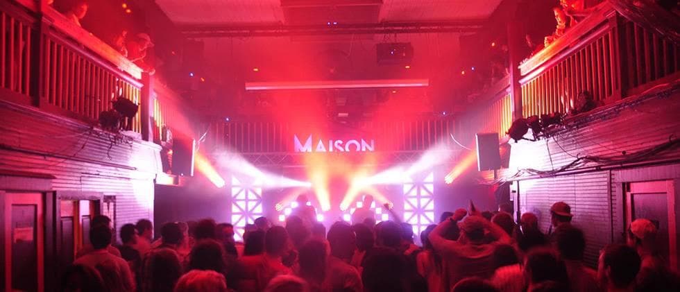 Live concert crowd under colorful stage lights at Maison