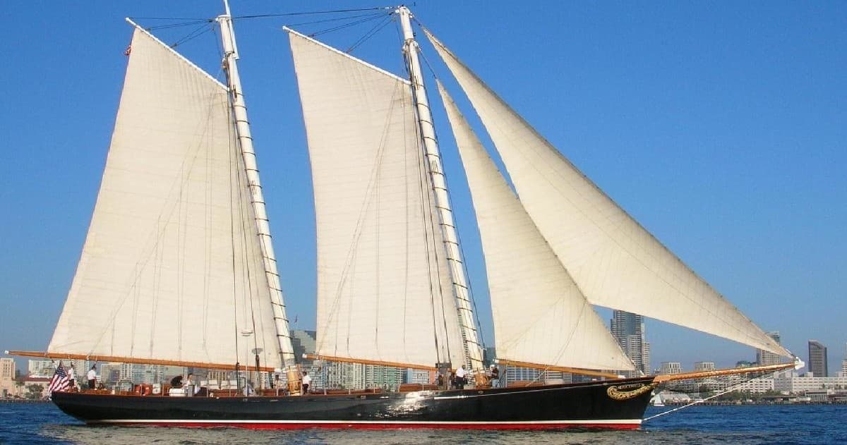 Historic schooner sailing off a sunny coastal city harbor