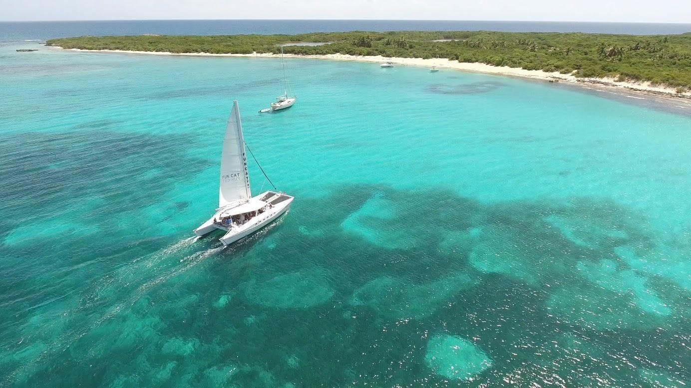 Aerial view of lone sailboat over shallow turquoise reef