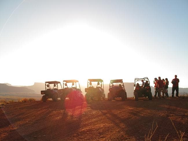 Sunset UTV convoy silhouetted on desert mesa, scenic off-road tour