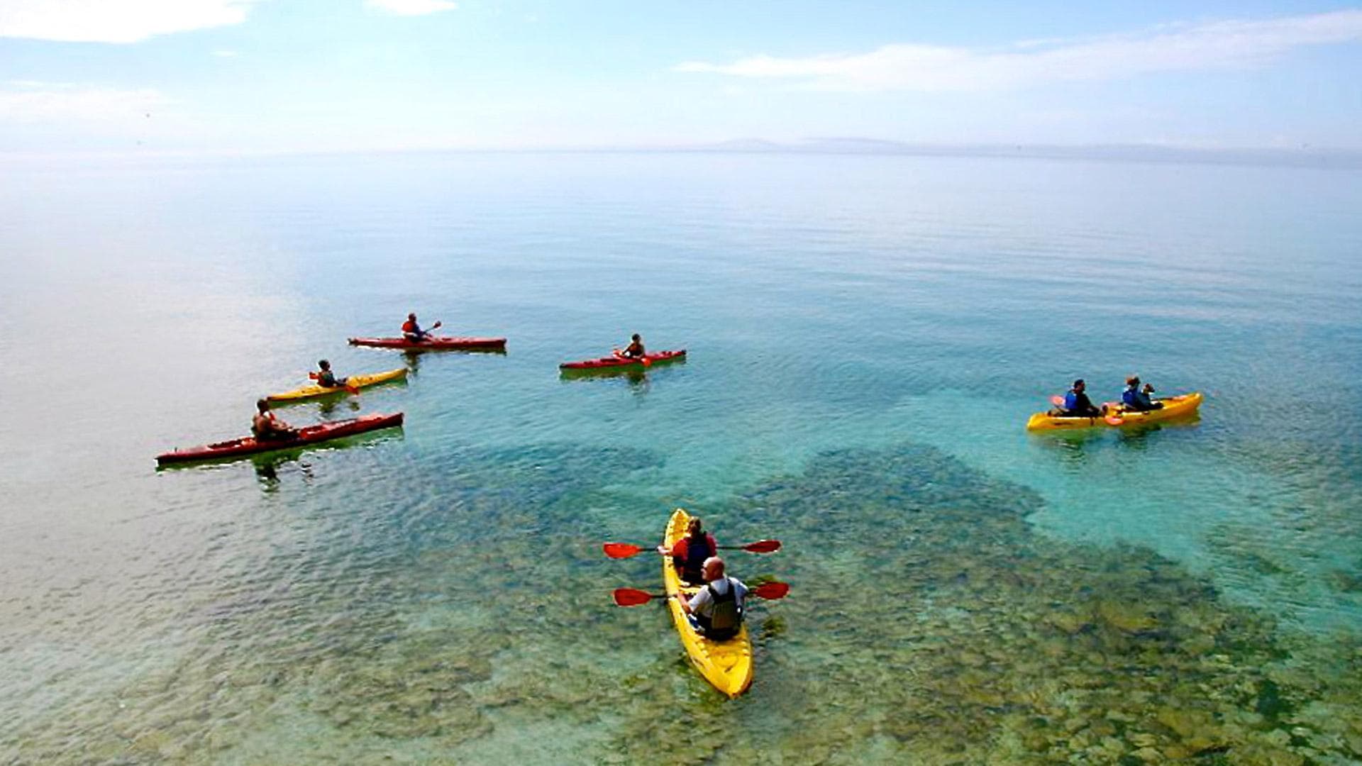 Sea kayakers paddling on crystal-clear Door County shoreline