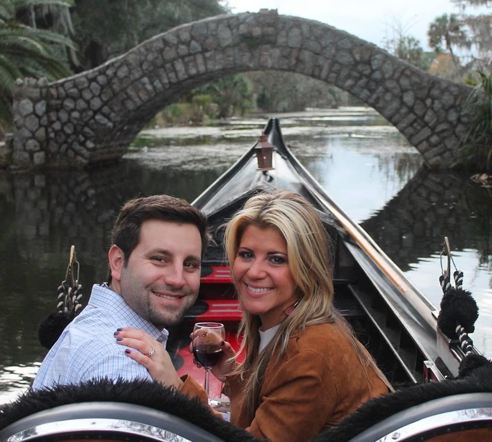Couple enjoying romantic gondola ride beneath arched stone bridge