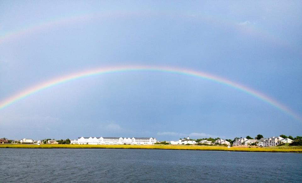 Double rainbow arching over coastal lagoon and shoreline homes
