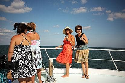 Group of friends on bow of boat enjoying sunny ocean cruise