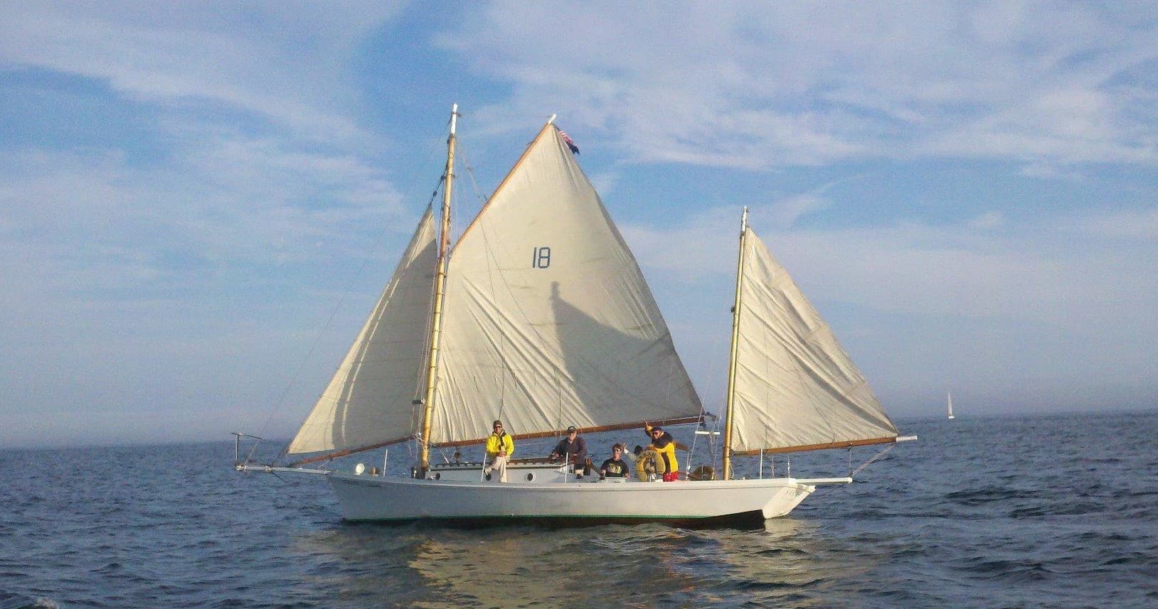 Two-masted sailboat cruising calm Pacific waters near shore