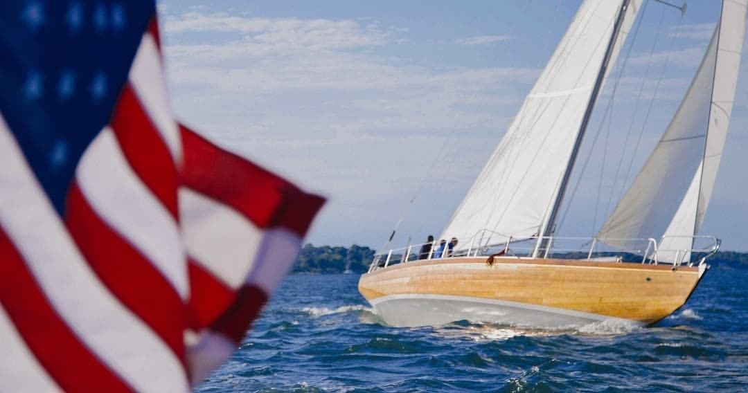 Sailboat with American flag skimming coastal waters, sailing action