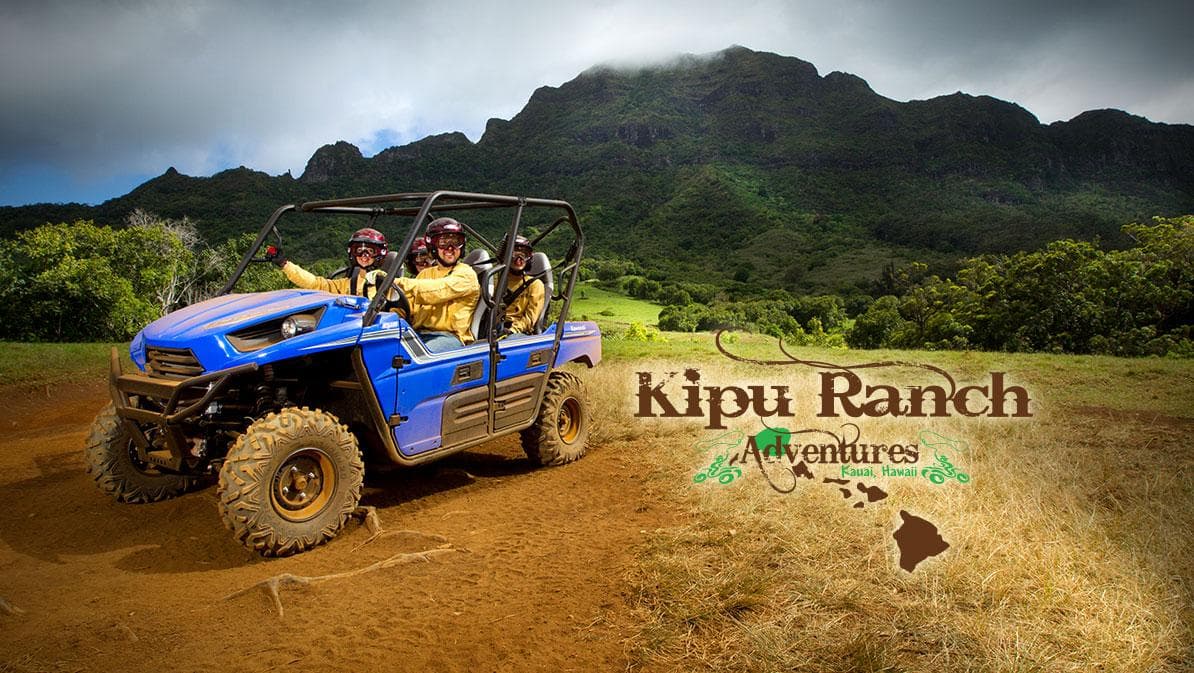 Blue UTV riding dusty ranch trail with mountains in background