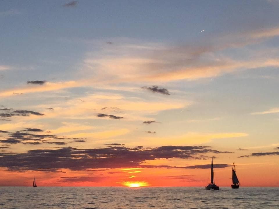 Sailboats silhouetted at vibrant sunset over open lake