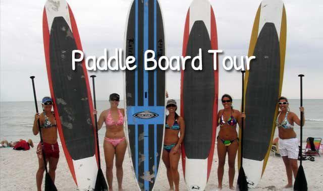 Group paddleboard tour on sandy beach with boards upright