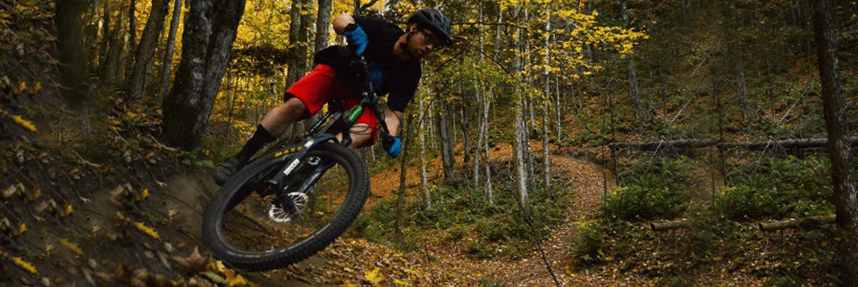 Downhill mountain biker carving a muddy forest trail