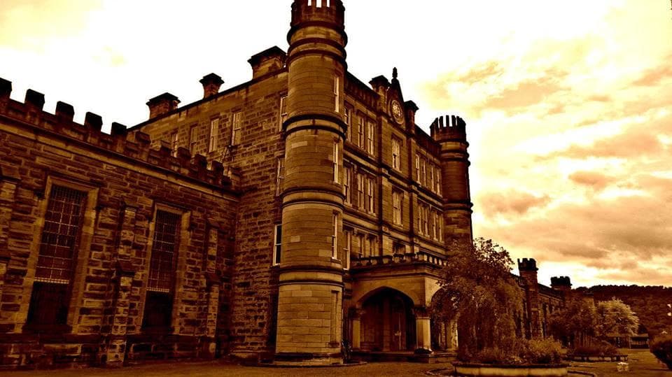 Historic stone penitentiary building exterior with dramatic sky
