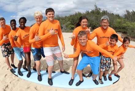 Surf class group on beach wearing orange rashguards in Hawaii