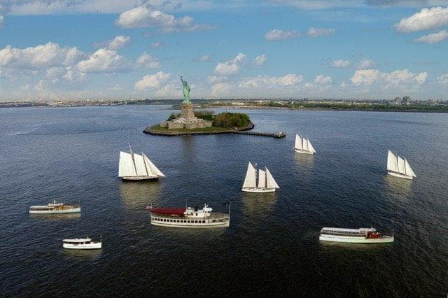 Tall ships sailing past Manhattan skyline at golden hour cruise