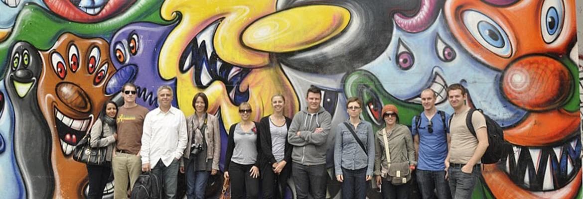 Group posing by vibrant alley mural, guided graffiti walking tour