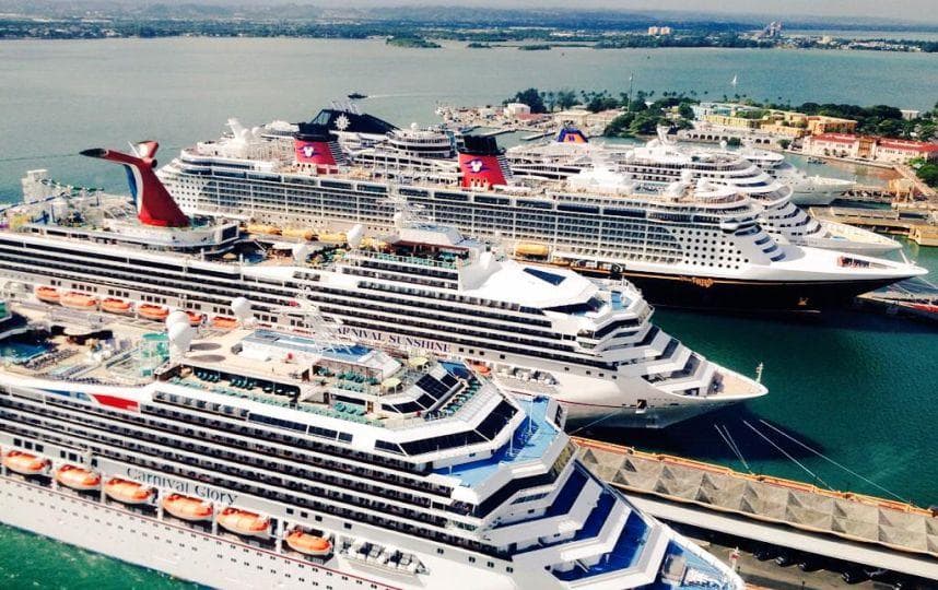 Aerial view of multiple cruise ships docked at a tropical port