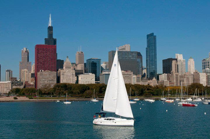 White sailboat cruising near Chicago skyline on calm Lake Michigan