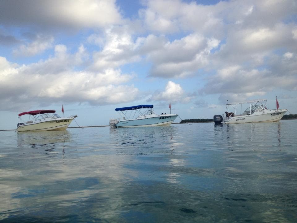 Scenic anchored boats reflecting on calm ocean under clouds