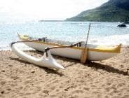 Twin-hulled outrigger canoe resting on tropical sandy shore