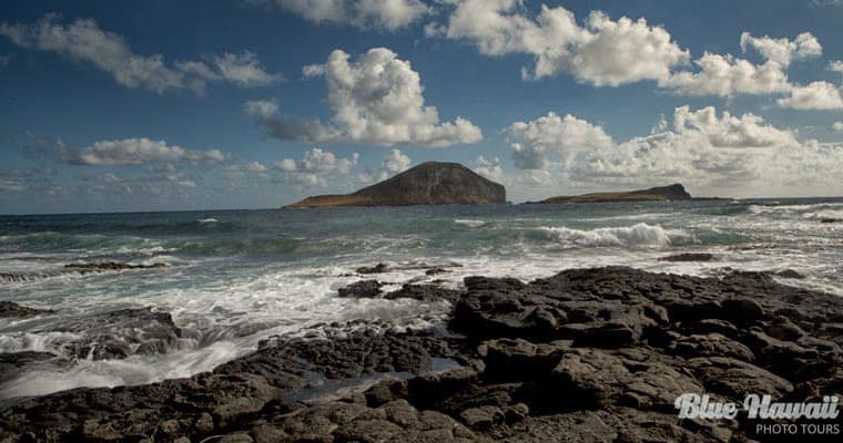 Rugged volcanic shoreline with waves and offshore islet view