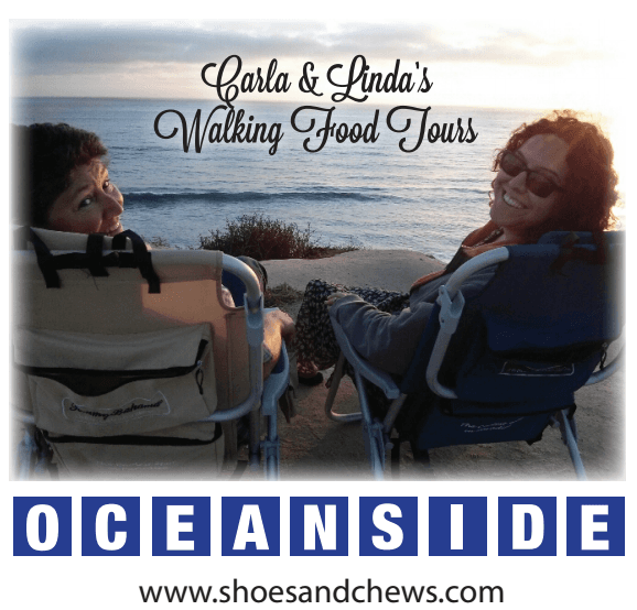 Two people seated on beach chairs at Oceanside sunset