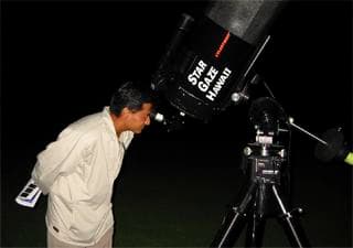 Guest peering through telescope on a nighttime stargazing tour