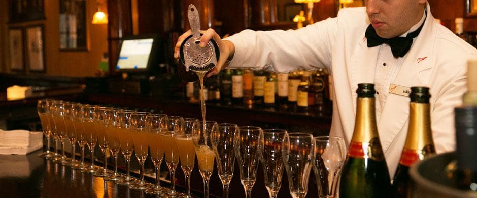 Bartender pouring champagne flutes at upscale indoor bar service