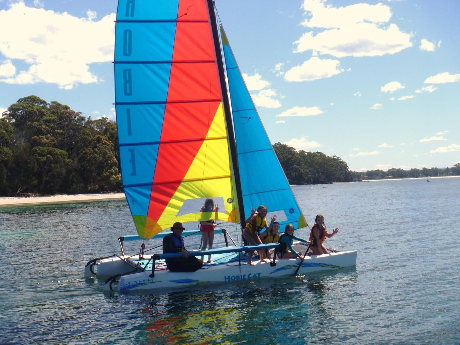 Colorful catamaran sailing with passengers on sunny coastal waters