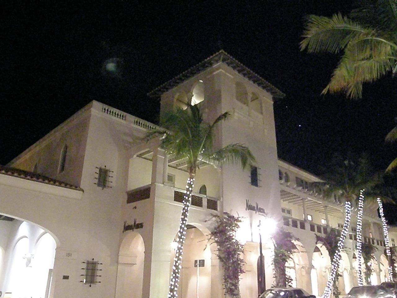 Illuminated Palm Beach beachfront building with palm trees at night