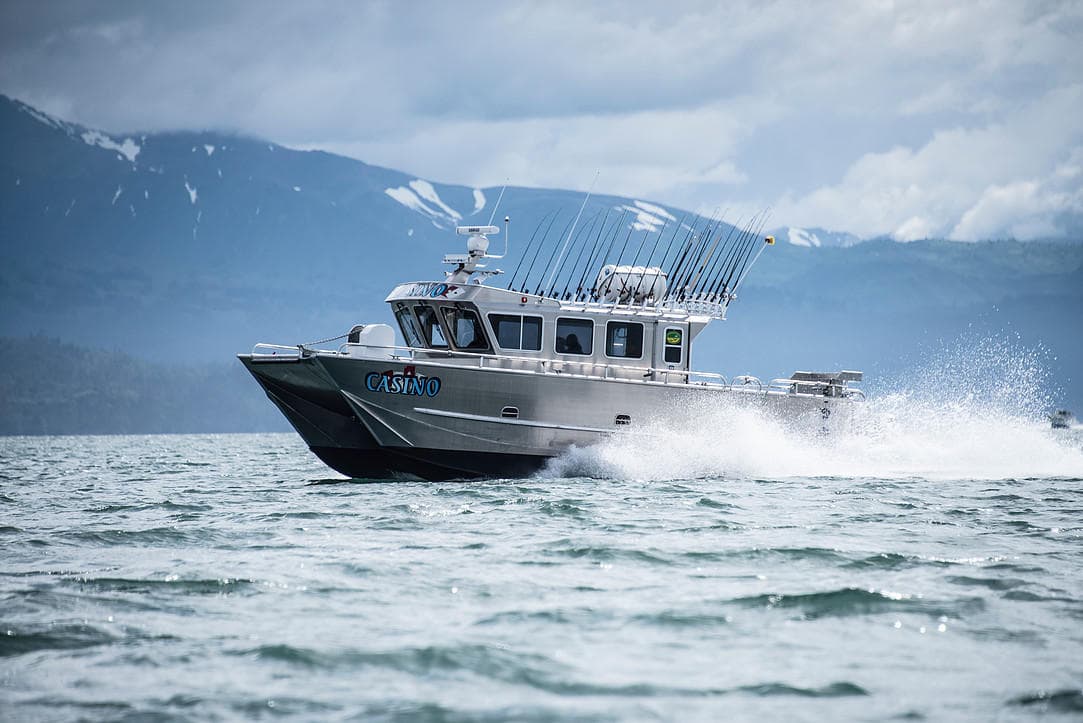 Charter fishing boat speeding through choppy Alaska coastal waters