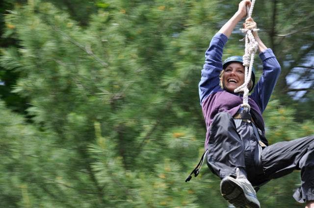 Adventurer zipping on canopy zipline through green forest