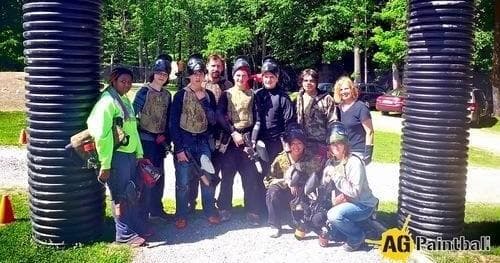 Group of paintball players posing outdoors at woodland field