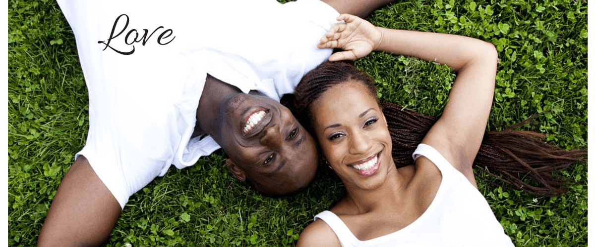 Couple lying on green lawn smiling outdoors in relaxed nature