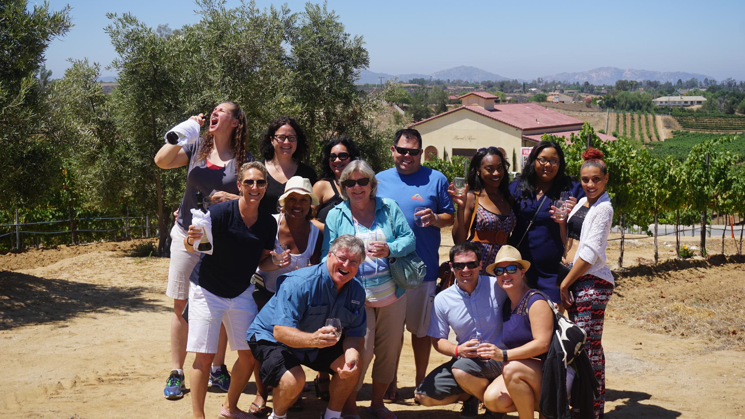 Large group posing on vineyard hill overlooking wine country