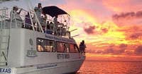 Tour boat cruising at sunset over coastal waters during golden hour