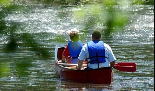 Two paddlers canoeing on a shaded river for outdoor adventure