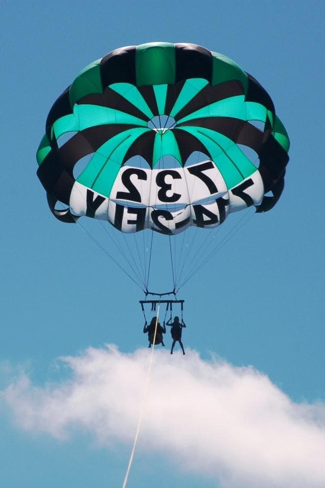 Green parasail soaring above ocean clouds at Point Pleasant