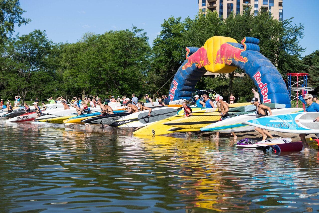 Busy paddleboard festival with colorful arch on lake